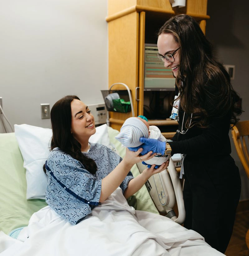 Provider handing new mother newborn in hospital room